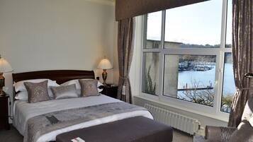 Una cama bien hecha con vistas a un puerto deportivo a través de amplias ventanas.