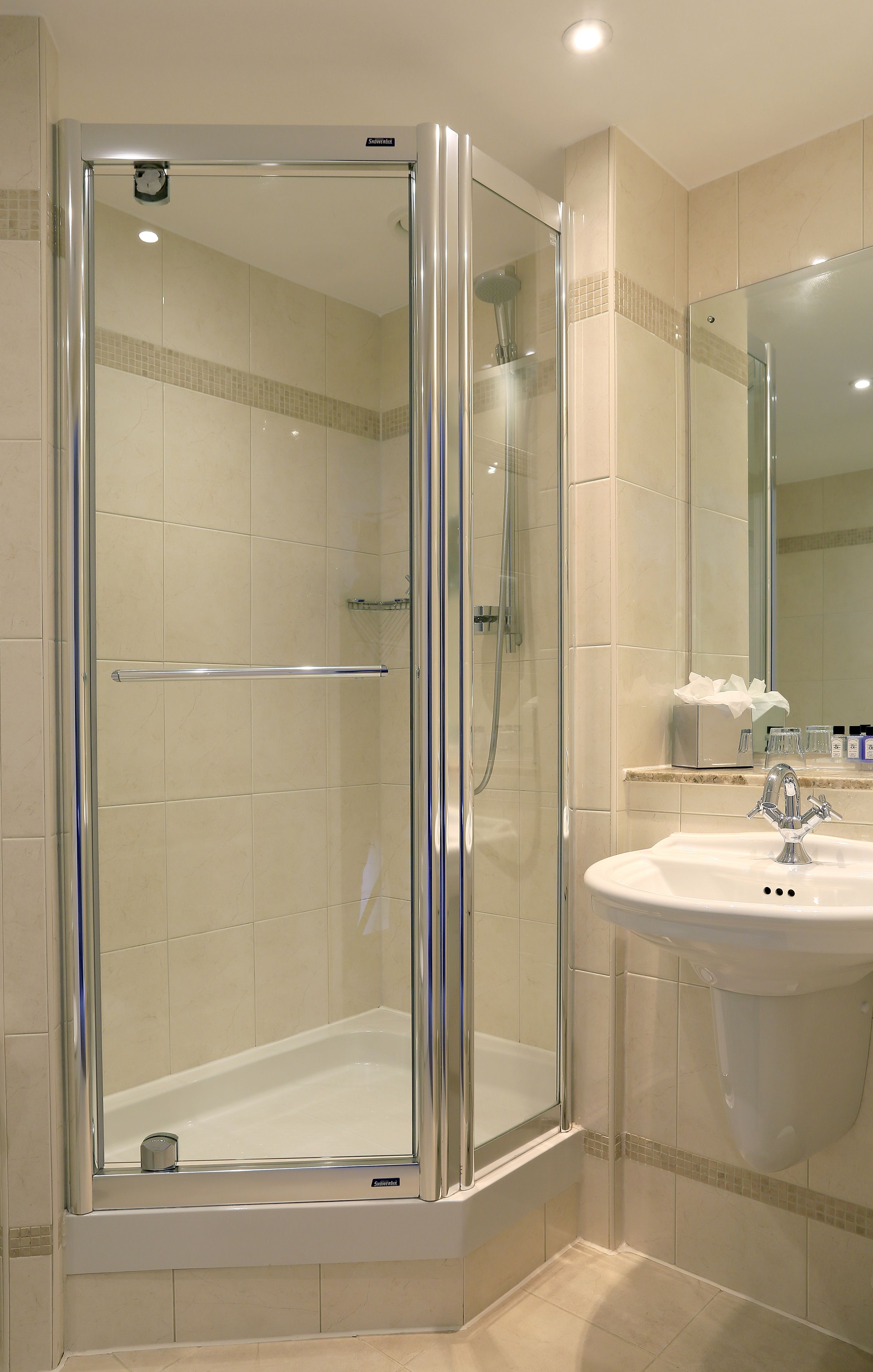 A modern bathroom with a glass-enclosed shower, a white sink, and a mirror above it.