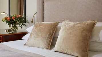 A neatly made bed with two beige pillows and a white bedspread.