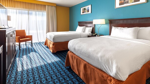 A hotel room with two beds, a desk, and a chair. -  Chester Inn & Suites (Sharonville)