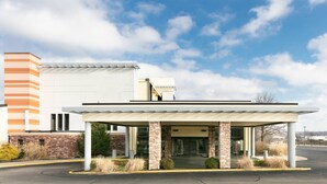 A modern building with a covered entrance, brick columns, and a parking lot. -  Chester Inn & Suites (Sharonville)