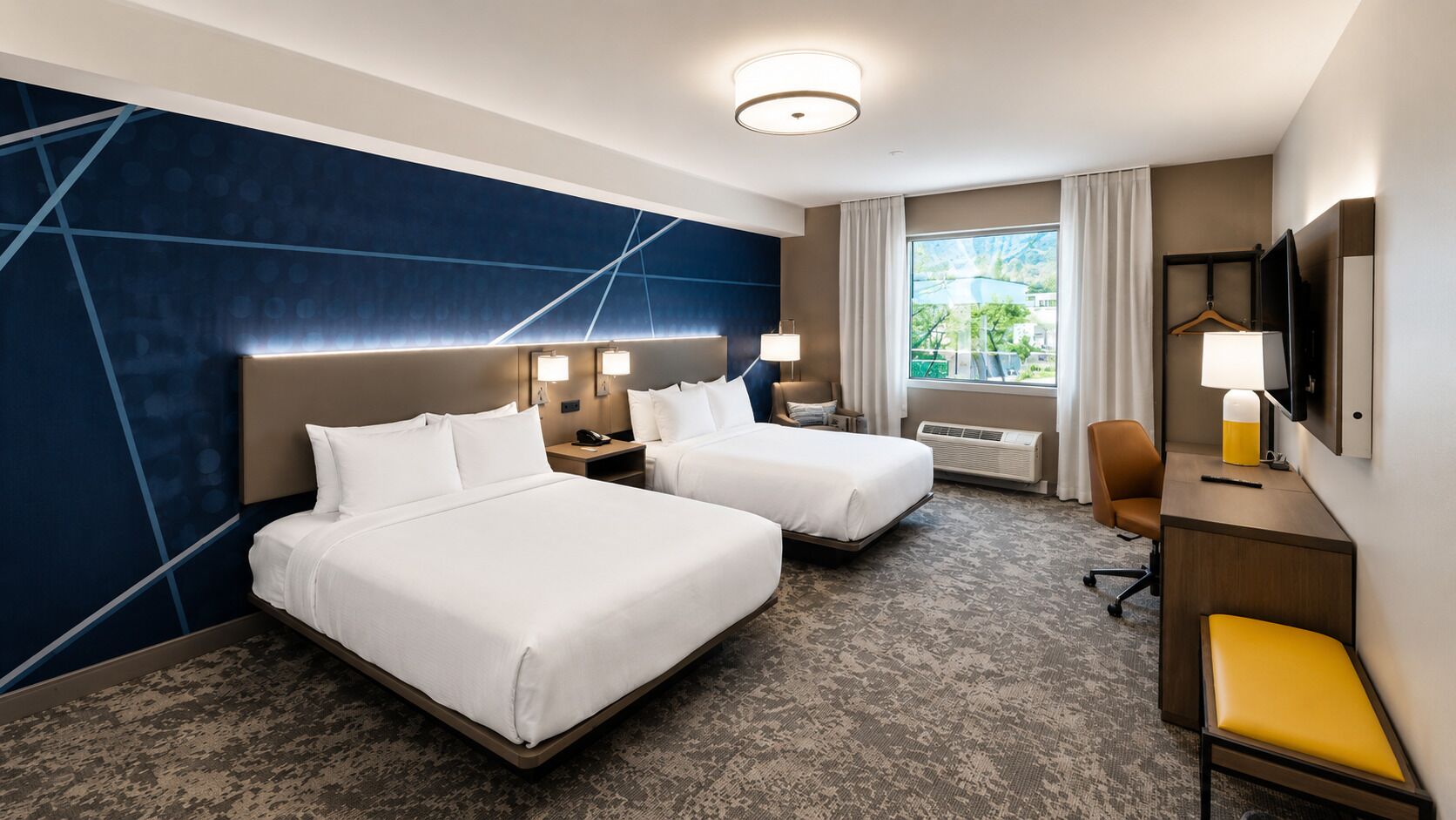 Habitación de hotel con dos camas, un escritorio, una silla, un televisor y una ventana con cortinas.