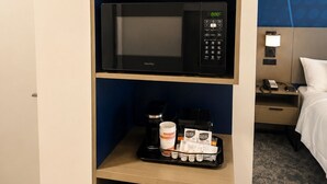 Habitación de hotel con minibar, microondas y refrigerador pequeño.
