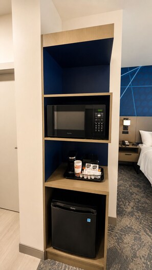 A hotel room with a minibar, a microwave, and a small refrigerator.