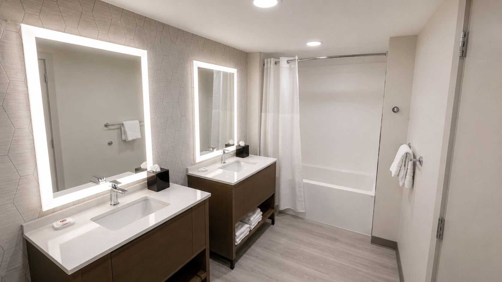 Un baño moderno con dos lavamanos, un espejo grande y una zona de ducha.
