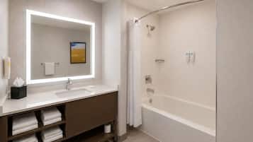 Un baño moderno con un espejo grande, un lavamanos, una ducha y un perchero para toallas.