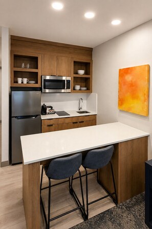 Une cuisine moderne équipée d’un four à micro-ondes encastré, d’un réfrigérateur et d’un plan de travail blanc.