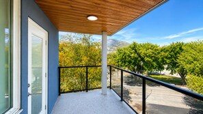 Un balcon avec vue sur les arbres et une montagne en arrière-plan.