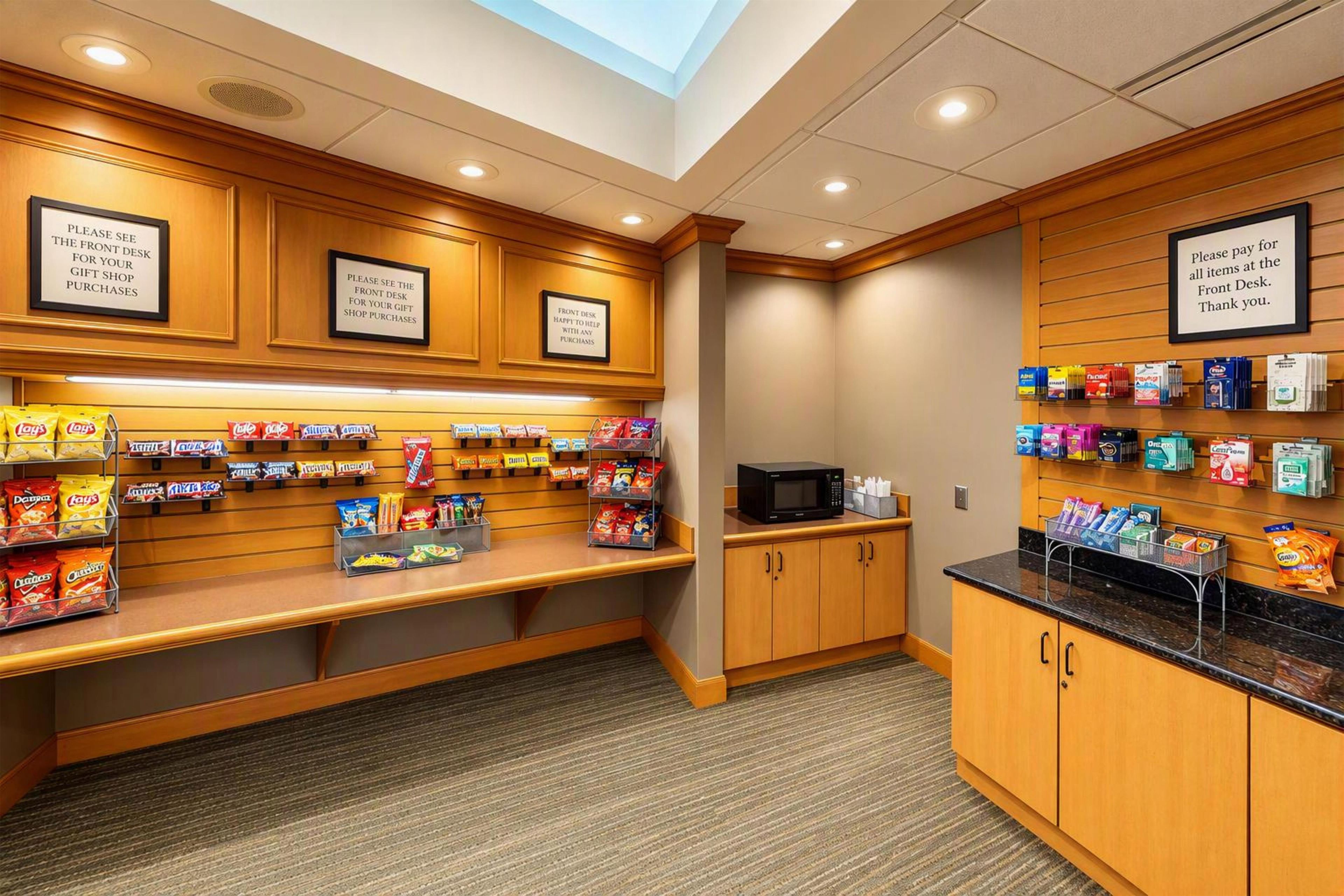 A gift shop with snack displays and a microwave. Signs direct to the front desk for purchases.