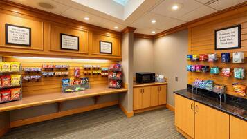 A gift shop with snack displays and a microwave. Signs direct to the front desk for purchases.