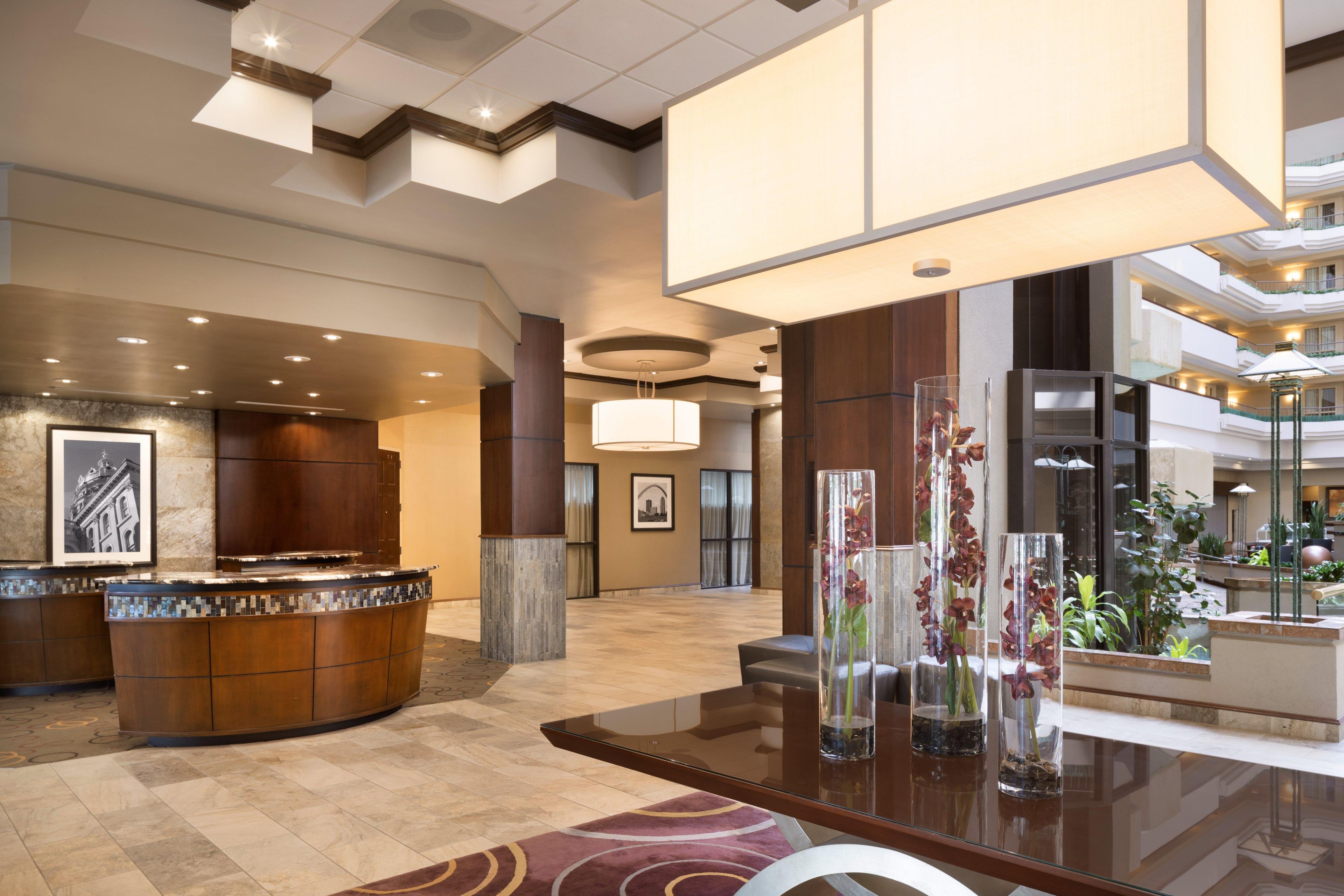 A hotel lobby with a reception desk, a glass-top table, and a large chandelier.