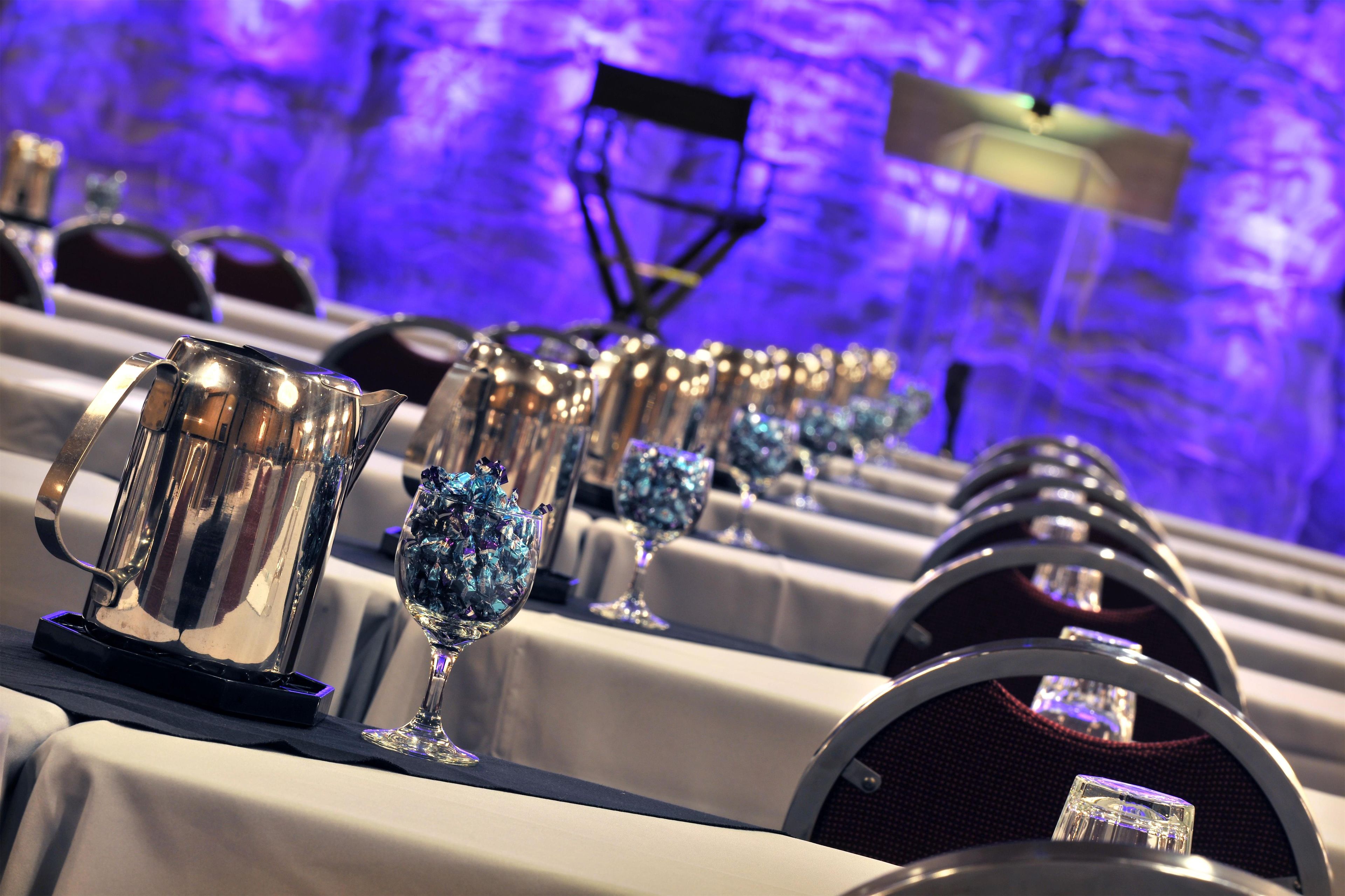 A row of tables with crystal glasses and silver pitchers, likely for a formal event.