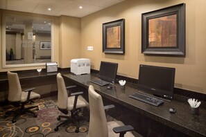 A hotel reception area with a long counter, multiple computer stations, and framed artwork on the wall. - Embassy Suites Hotel Des Moines Downtown (Des Moines)