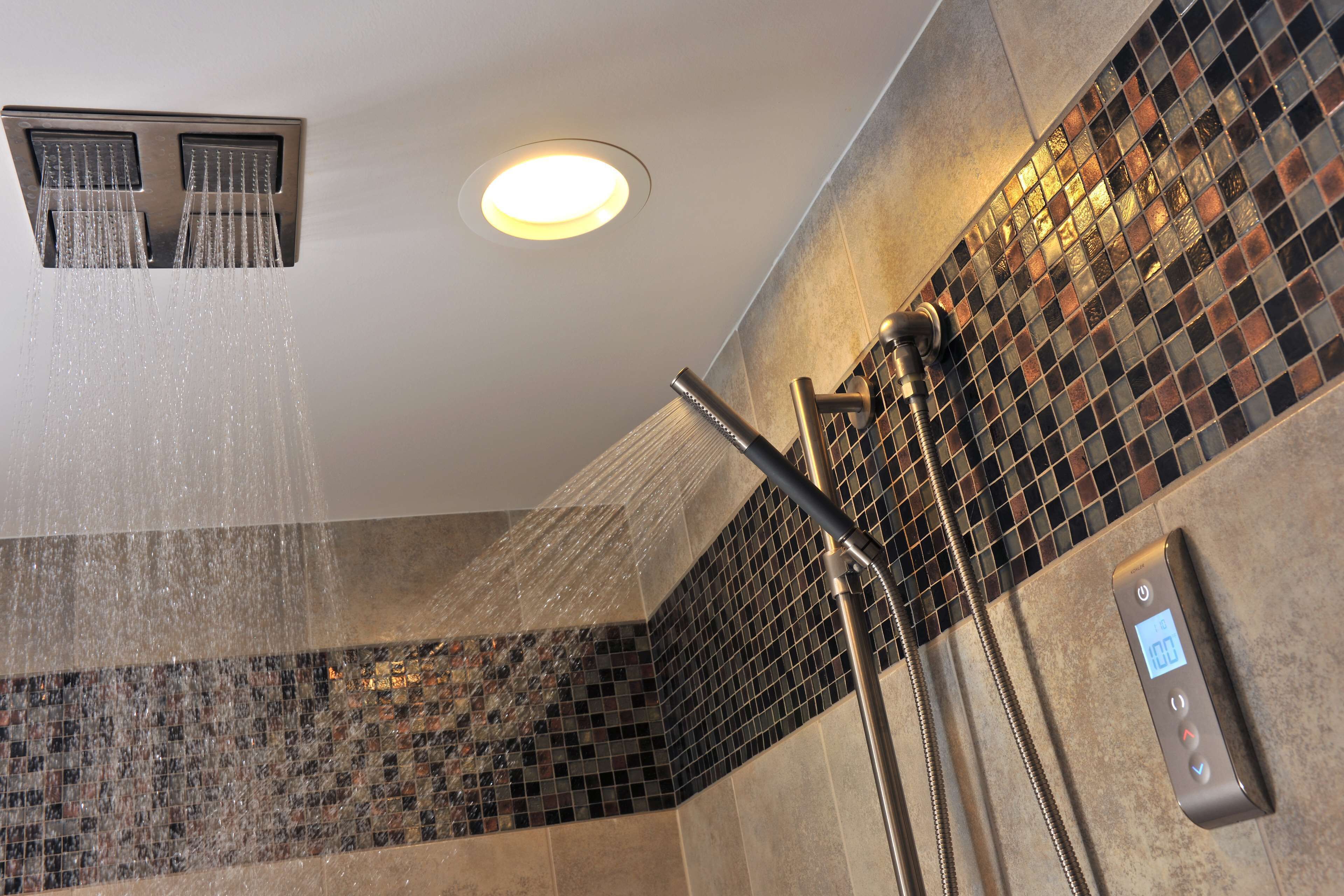 A modern shower with multiple water jets, a control panel, and a tiled wall with a mosaic pattern.