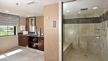 A modern bathroom with a glass-enclosed shower, a vanity with a mirror, and a window with blinds.