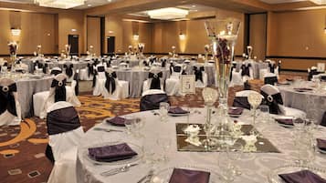 A banquet hall with round tables, each set with white tablecloths, black sashes, and numbered place cards.
