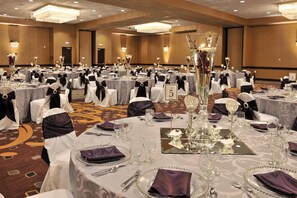 A banquet hall with round tables, each set with white tablecloths, black sashes, and numbered place cards. - Embassy Suites Hotel Des Moines Downtown (Des Moines)