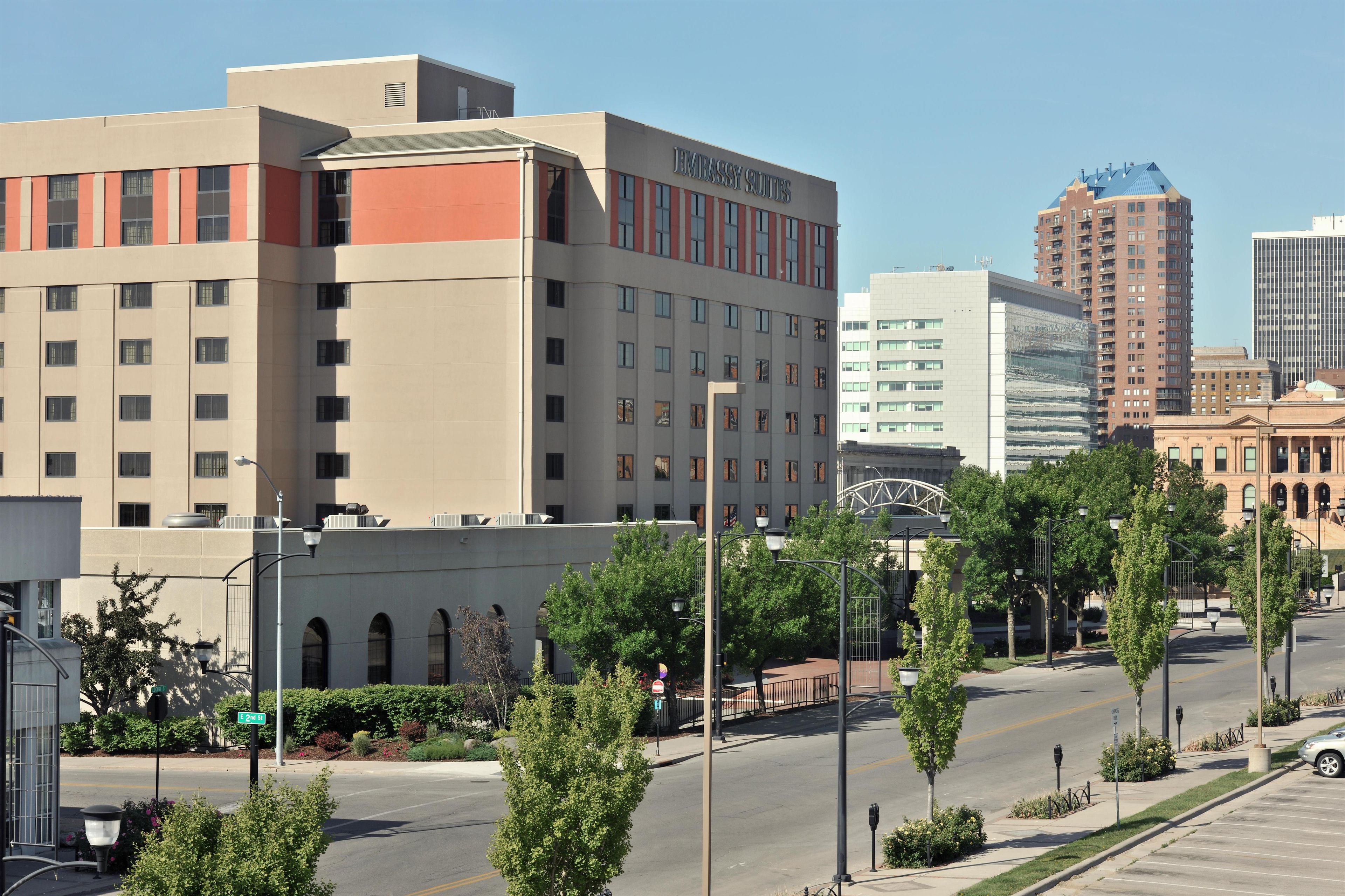 Un edificio de varios pisos con un cartel que dice 'EMBASSY SUITES', indicando un hotel.