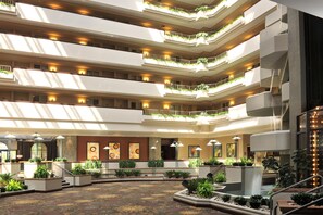 Un vestíbulo de hotel de varios niveles con balcones, obras de arte y plantas de interior.