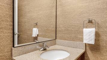 A bathroom with a granite countertop sink, a mirror, and a towel rack.