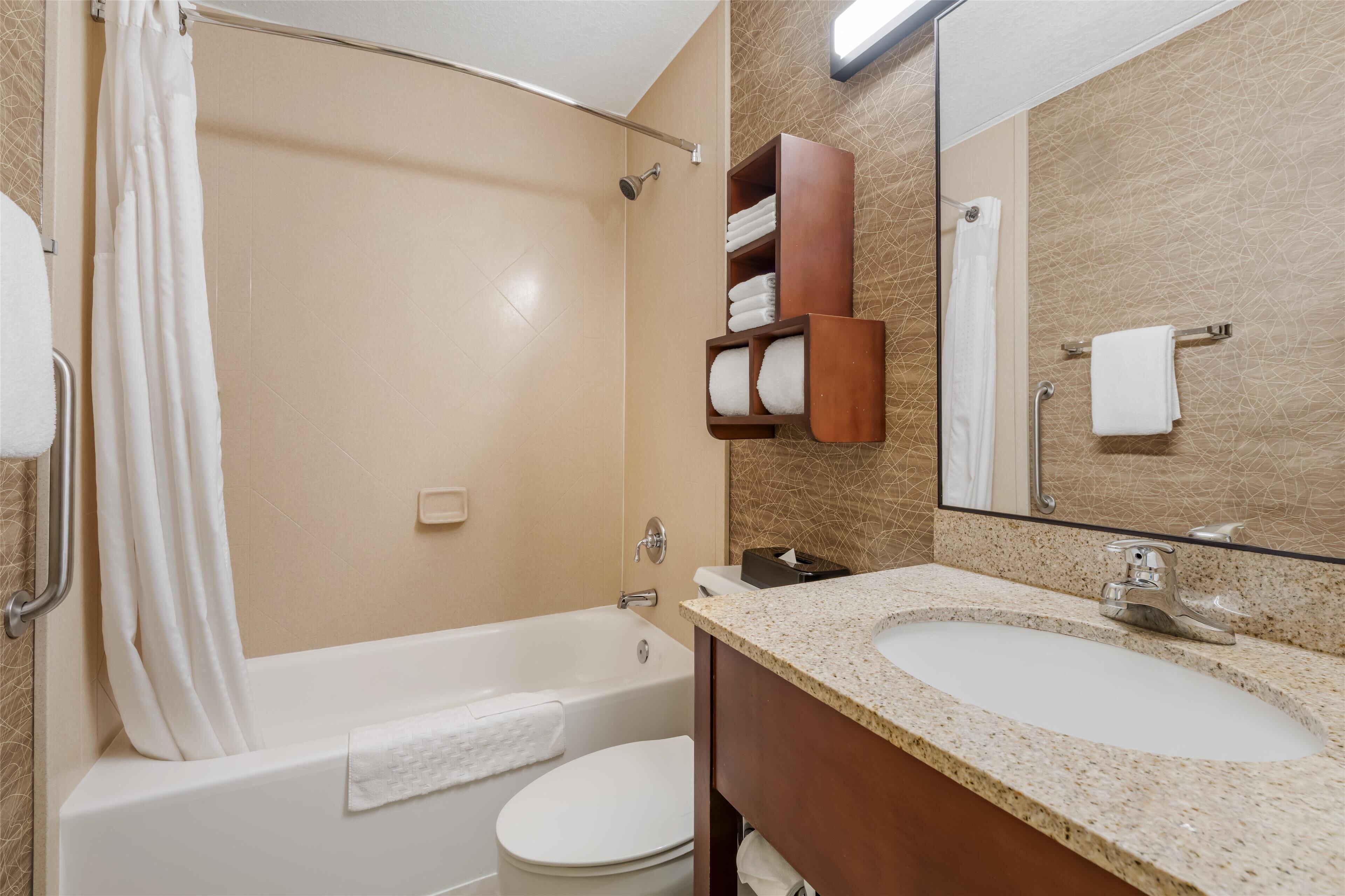 A bathroom with a bathtub, toilet, and a vanity with a sink.