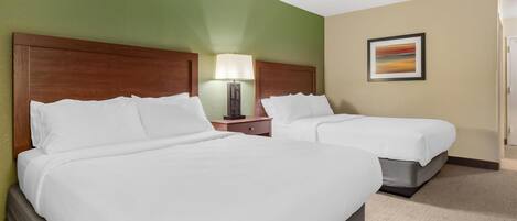 A hotel room with two beds, a nightstand with a lamp, and a painting on the wall.