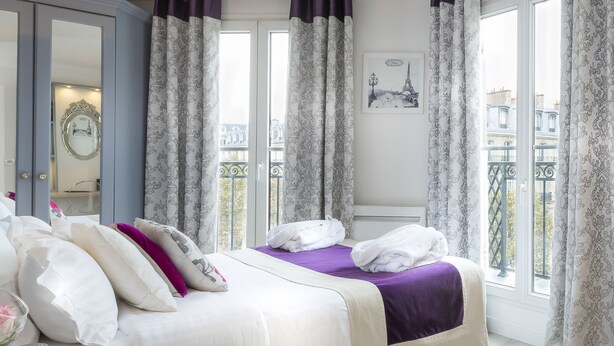 Habitación de hotel con cama, espejo y ventana con cortinas.
