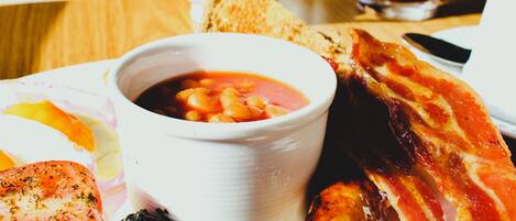 Un plato de desayuno con salchichas, tocino, tomates y frijoles.