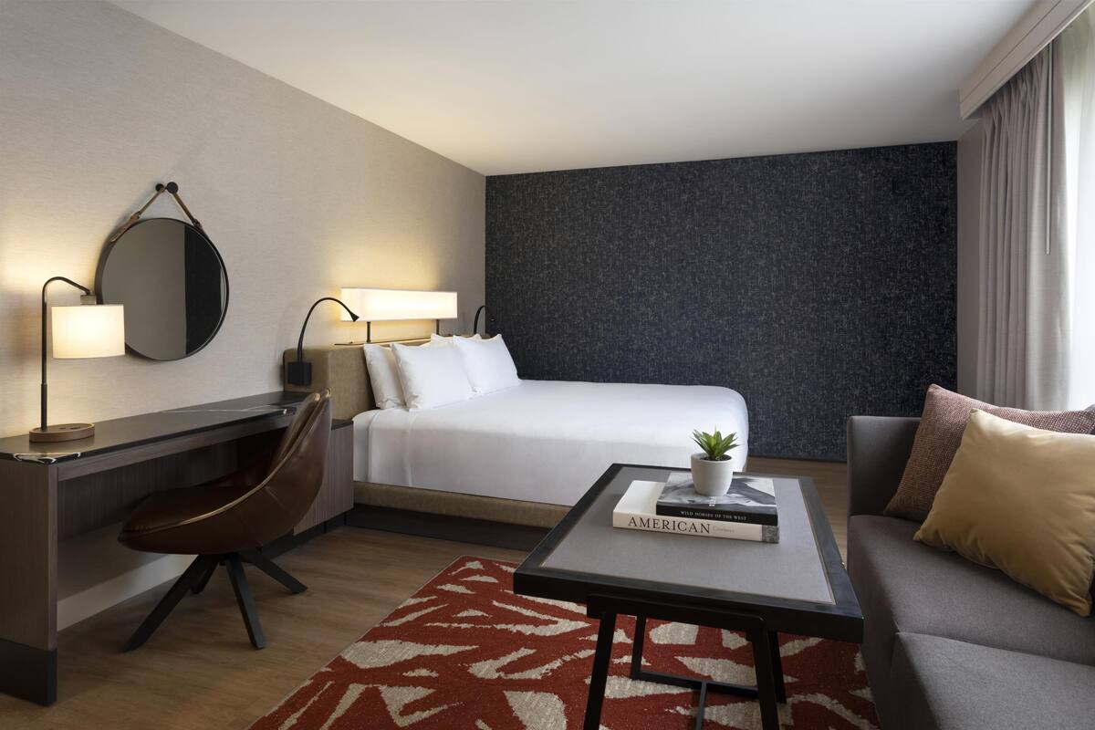 Una habitación de hotel con cama, escritorio, silla y sofá.