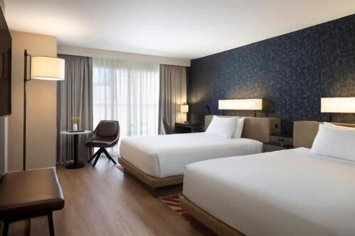 Una habitación de hotel con dos camas, un escritorio, una silla y un televisor.