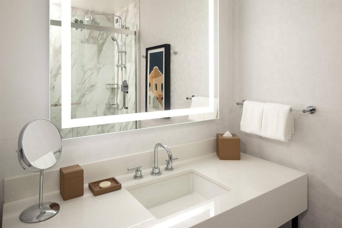 Un baño moderno con un espejo grande, un lavabo, un perchero para toallas y un cuadro enmarcado en la pared.