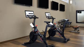A gym with stationary bikes, exercise equipment, and a large mirror.