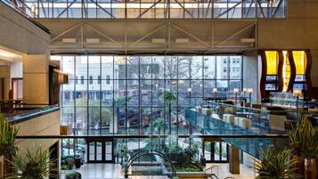 A spacious atrium with a glass ceiling, multiple levels, and indoor plants.