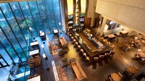 Amplia sala de estar con diversas opciones de asientos, un bar central y grandes ventanales que ofrecen vistas.