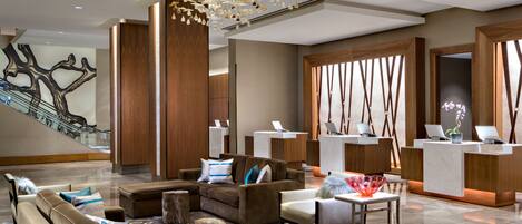 A modern lobby with a reception desk, seating area, and a staircase.