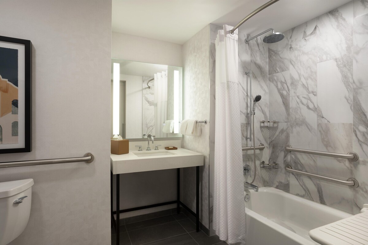 Une salle de bain avec une douche en marbre, un lavabo avec un miroir et des toilettes.
