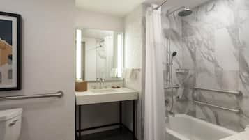 Un baño con ducha de mármol, lavabo con espejo y retrete.
