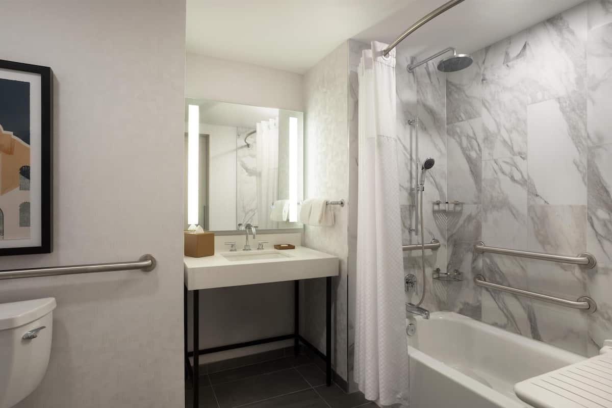Un baño con ducha de mármol, lavabo con espejo y retrete.