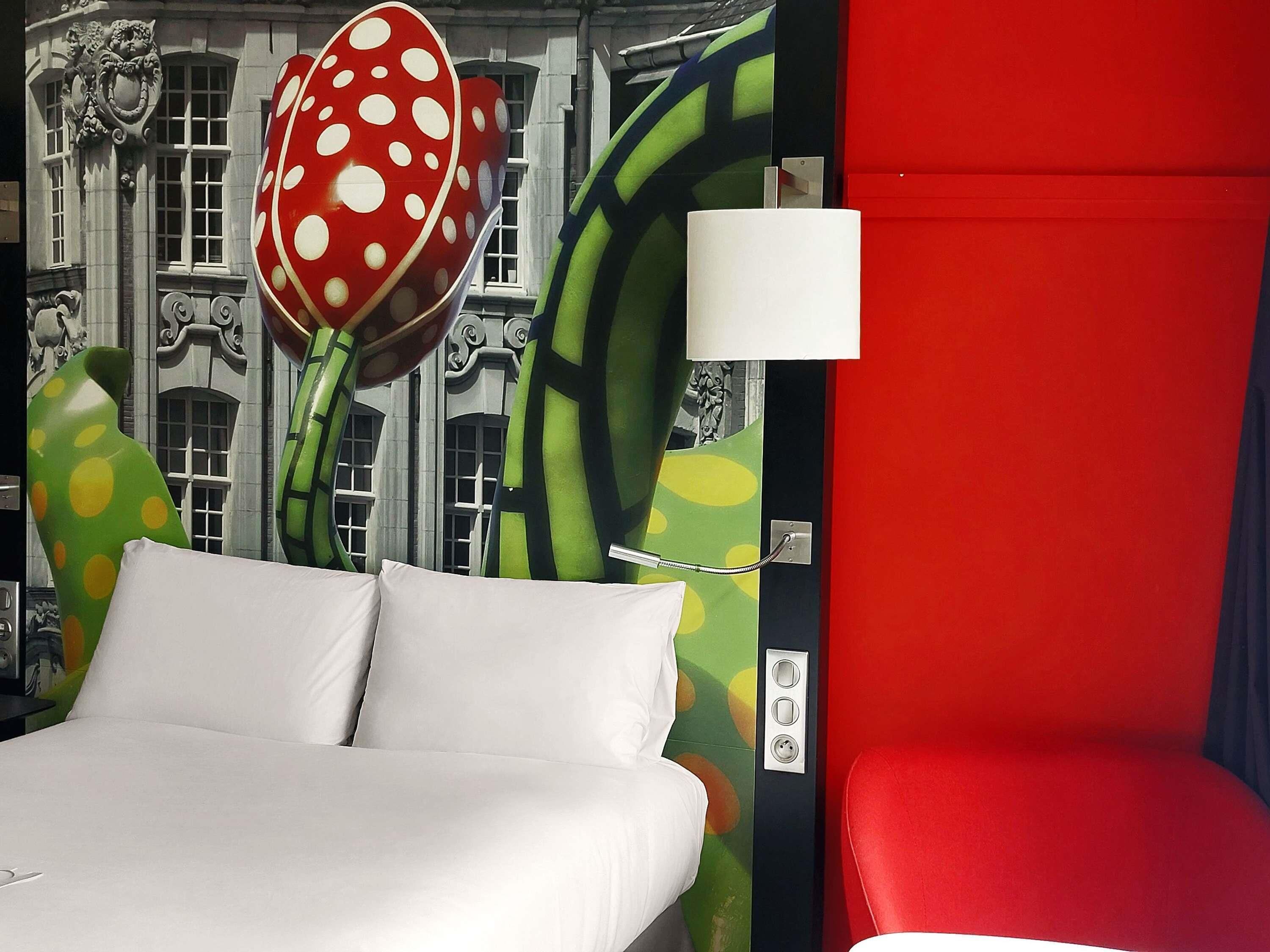 Ein Bett mit weißen Leinen, einer roten Wand und einer Wand mit grün-gelbem Muster.