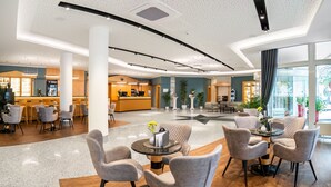 A spacious lobby with a reception desk, seating area, and a coffee bar. - Andante Hotel Dresden (Dresden)