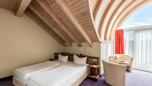 A hotel room with a large bed, a desk, a chair, and a window with curtains. - Andante Hotel Dresden (Dresden)