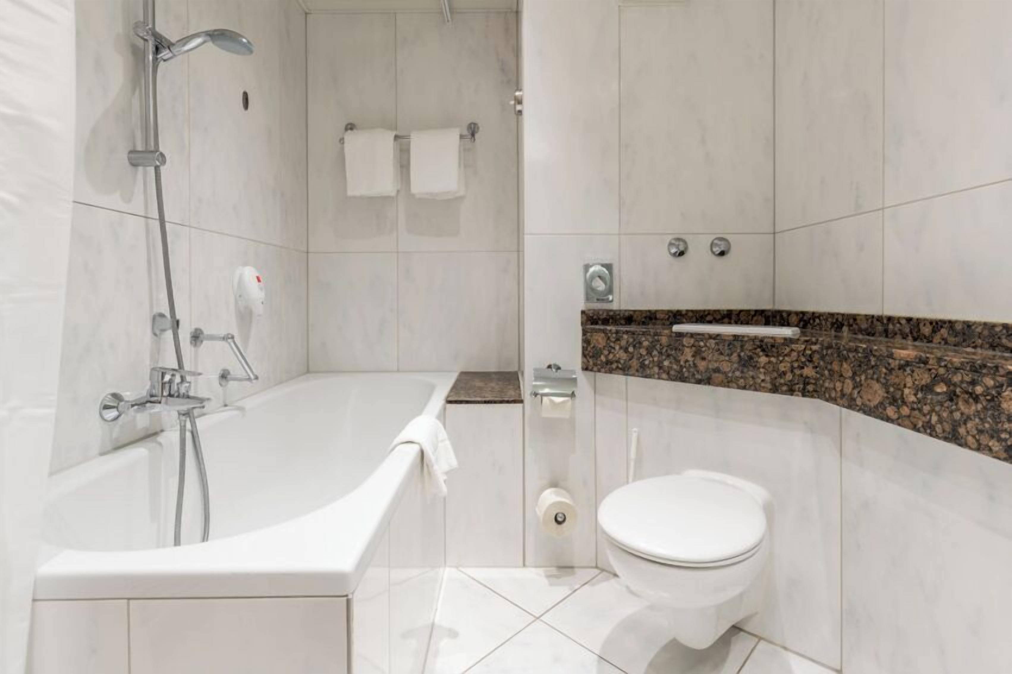 Ein modernes Badezimmer mit Badewanne, Toilette und Duschbereich.