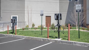 A parking area with electric vehicle charging stations, a sign indicating guest-only use, and a building with a flat facade.
