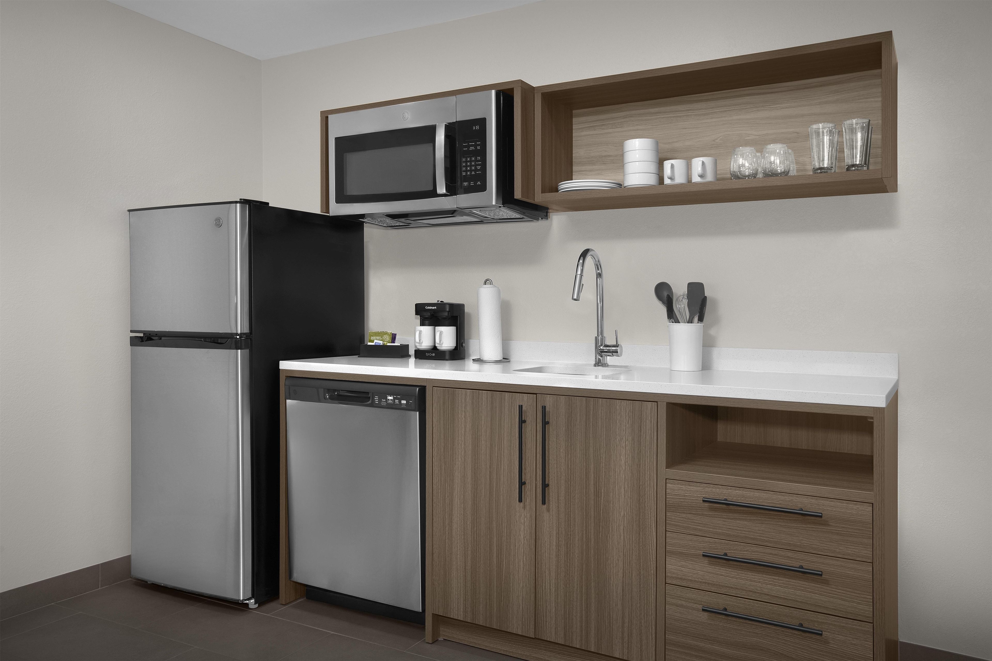 Eine moderne Küche mit Kühlschrank, Geschirrspüler, Mikrowelle und Holzschränken.