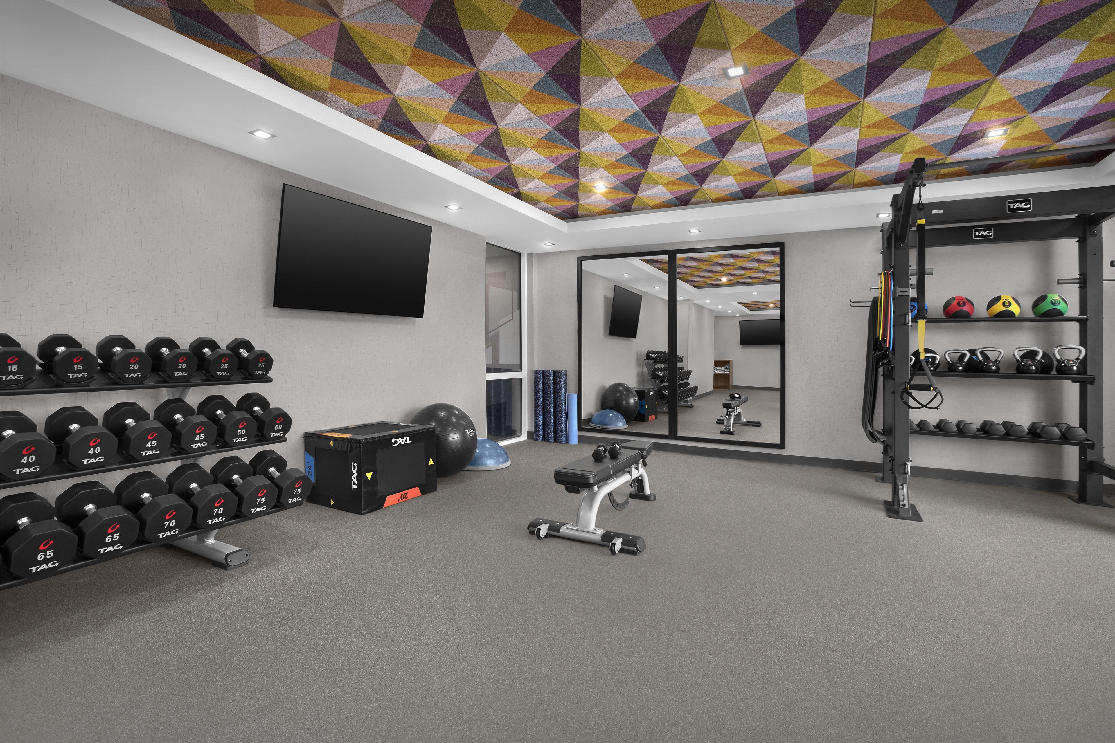 Una palestra con attrezzatura per sollevamento pesi, una TV e un soffitto decorato.