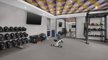Una palestra con attrezzatura per sollevamento pesi, una TV e un soffitto decorato.