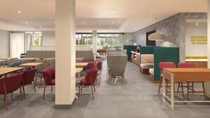 A modern dining area with tables and chairs, a counter, and a wall with a motivational quote. - Home2 Suites by Hilton Chelmsford Lowell (Chelmsford)