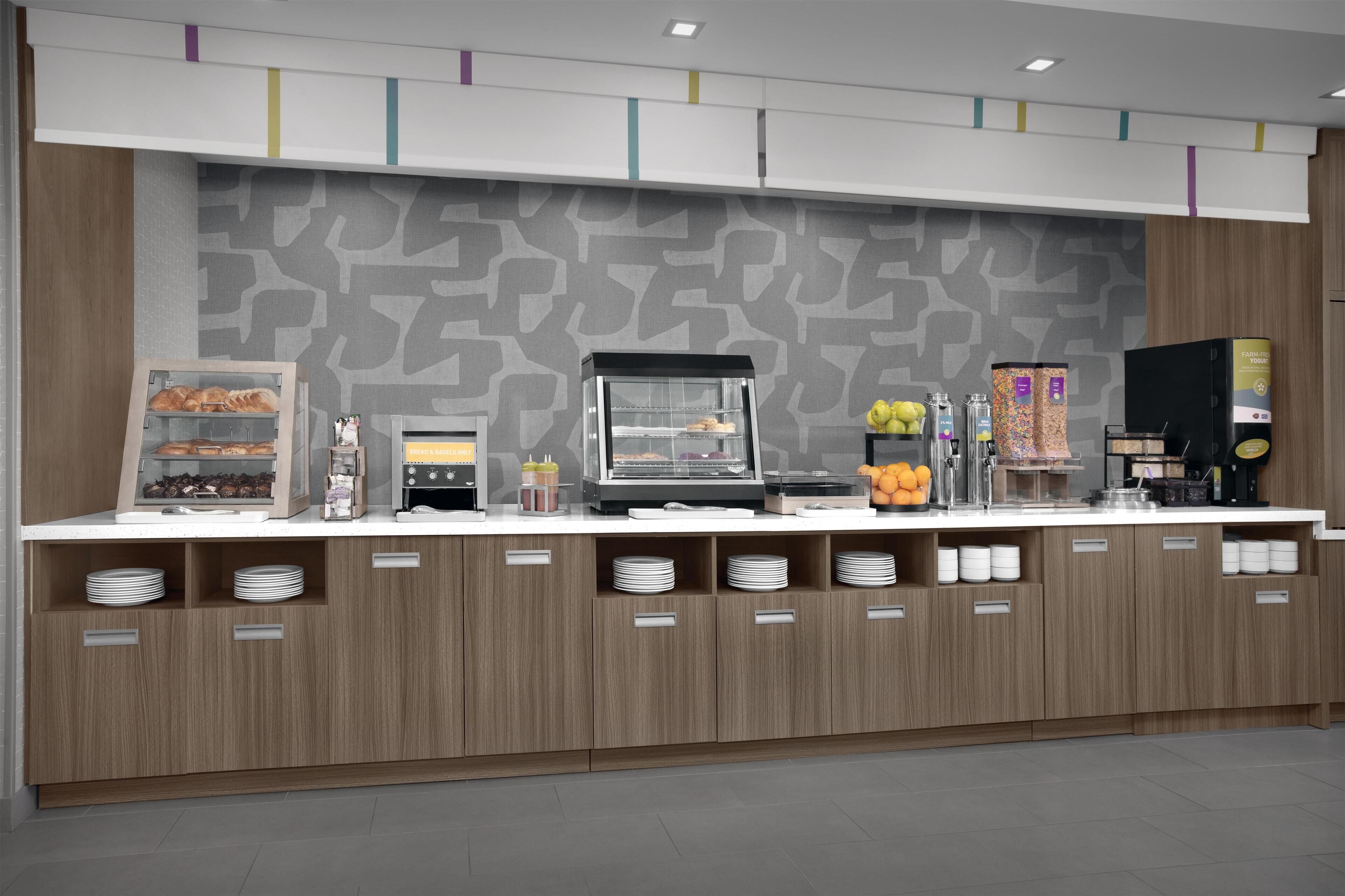 A modern breakfast bar with a coffee machine, a fruit display, and a refrigerated section.