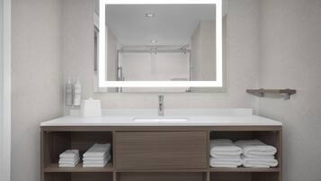 Un baño con lavamanos blanco, un espejo y estantes de madera con toallas dobladas.