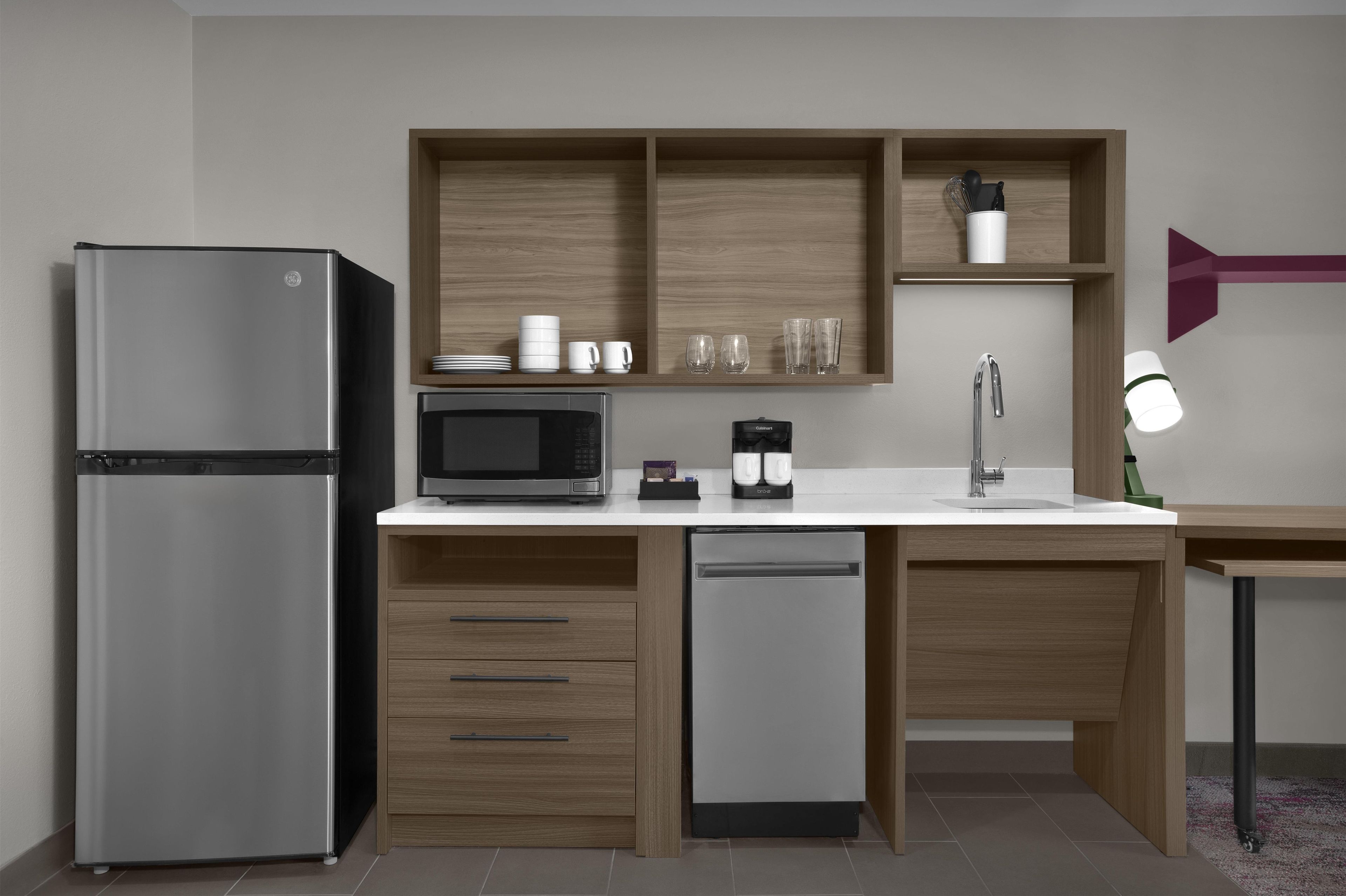 A modern kitchen with a refrigerator, microwave, coffee maker, and a sink.